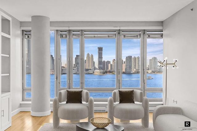 living area featuring a view of city, a water view, baseboards, and wood finished floors