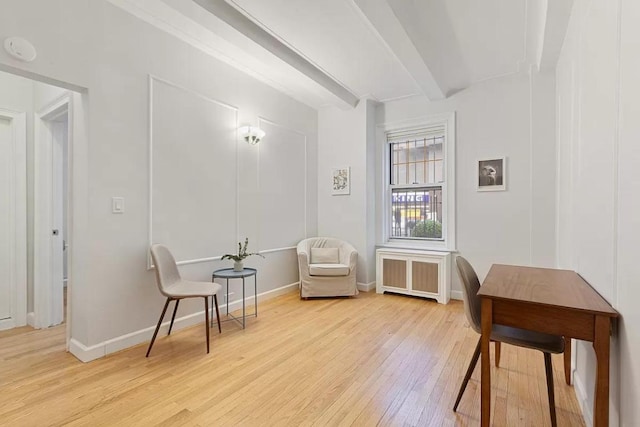 living area with light wood-type flooring, beamed ceiling, and radiator