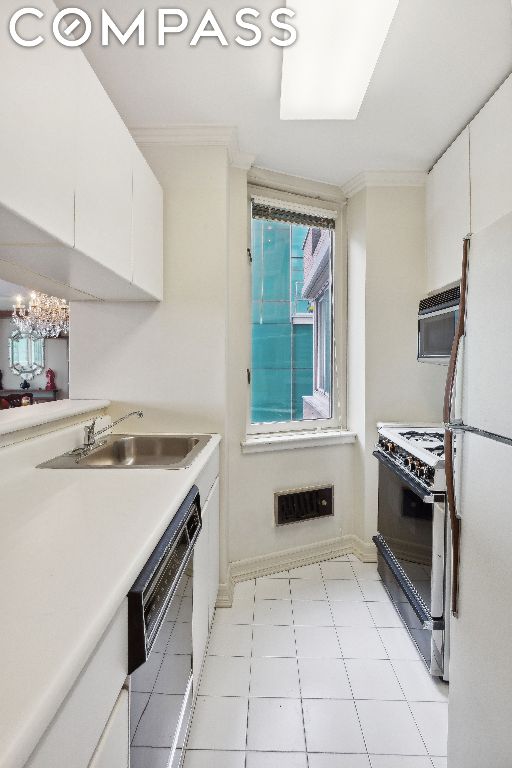 kitchen with range with gas stovetop, white cabinetry, black dishwasher, white refrigerator, and ornamental molding