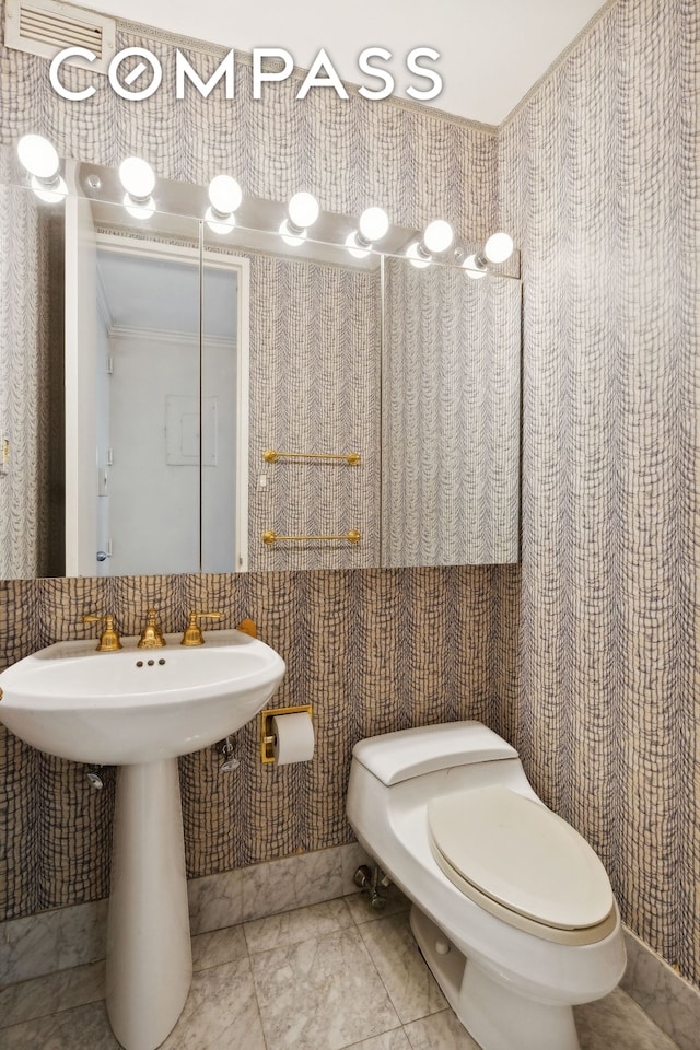 half bath featuring toilet and marble finish floor