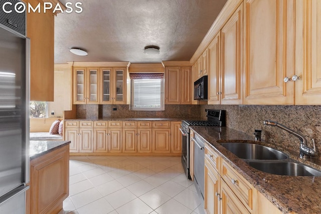 kitchen with light brown cabinets, sink, dark stone countertops, and stainless steel appliances