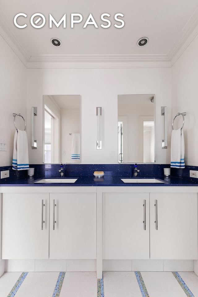 bathroom featuring crown molding, double vanity, and a sink