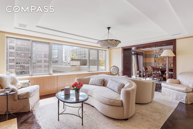 living area with a tray ceiling and visible vents