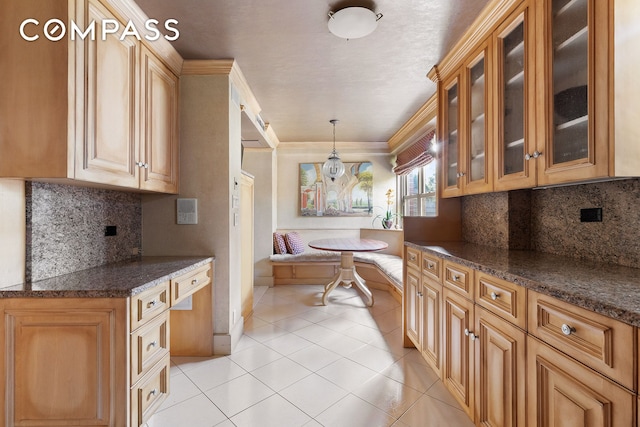 kitchen featuring light tile patterned floors, ornamental molding, glass insert cabinets, decorative light fixtures, and breakfast area