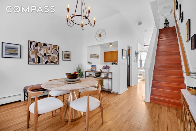 dining area with stairs, a high ceiling, light wood-type flooring, and a baseboard radiator