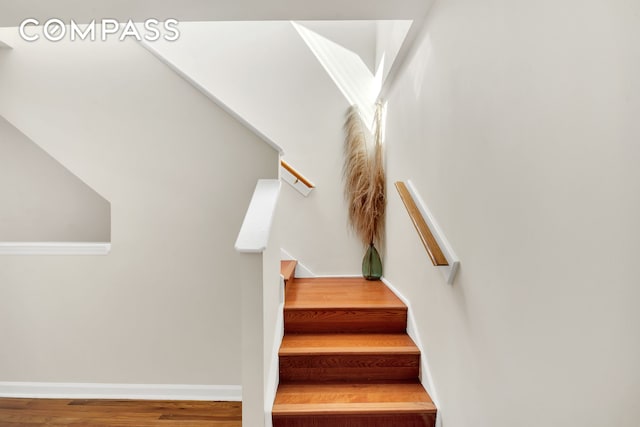 staircase featuring baseboards and wood finished floors