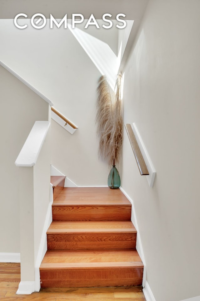 stairway with wood finished floors and baseboards