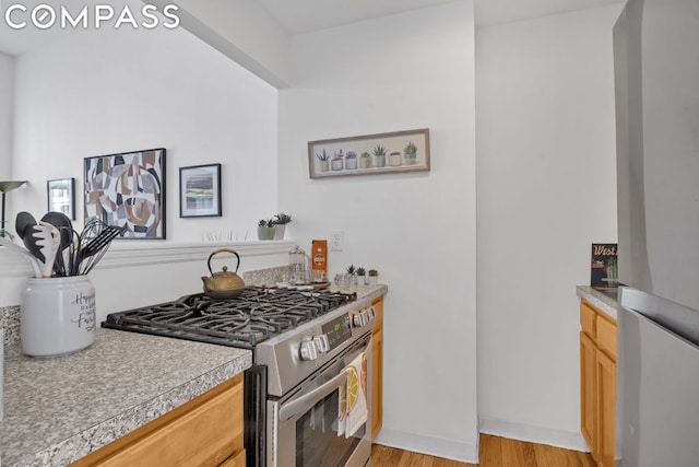 kitchen featuring light brown cabinetry, stainless steel appliances, and light hardwood / wood-style floors