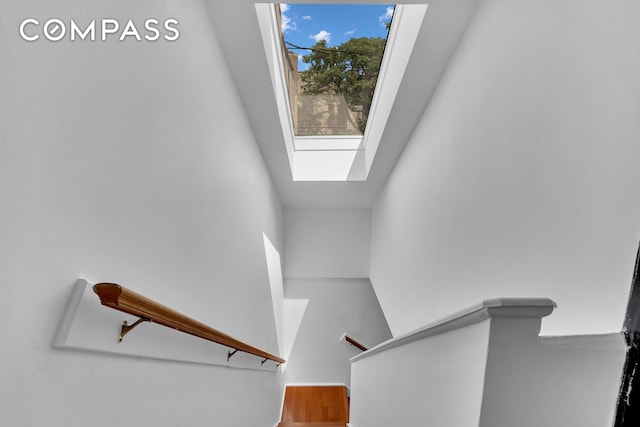 stairs featuring a skylight and wood finished floors