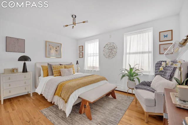 bedroom with an inviting chandelier, light hardwood / wood-style floors, and multiple windows