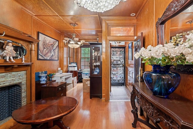 interior space featuring crown molding, light wood-type flooring, a notable chandelier, and wooden walls