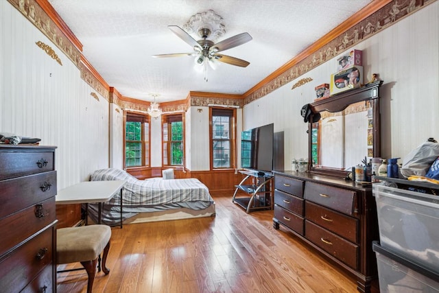 bedroom with a textured ceiling, ornamental molding, ceiling fan, and light wood-type flooring