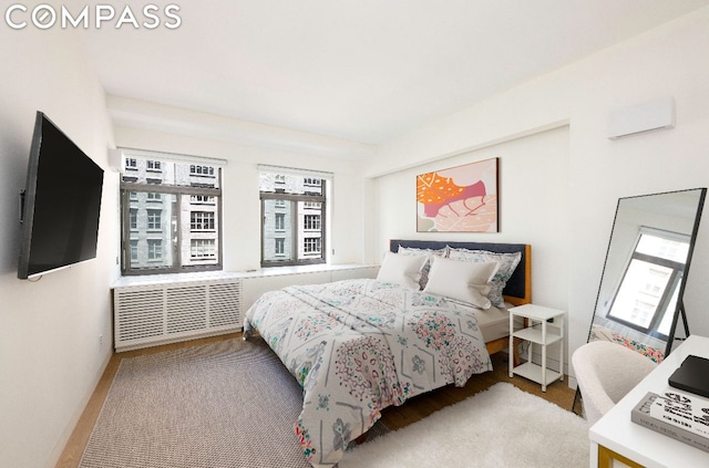 bedroom with hardwood / wood-style flooring, radiator, and a wall mounted AC