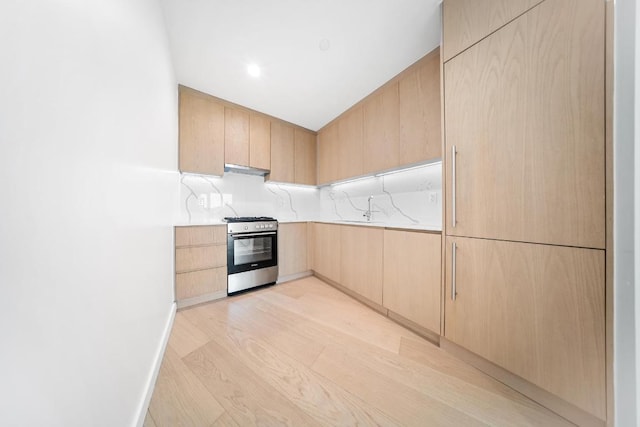 kitchen with stainless steel gas stove, light wood finished floors, modern cabinets, light countertops, and light brown cabinetry