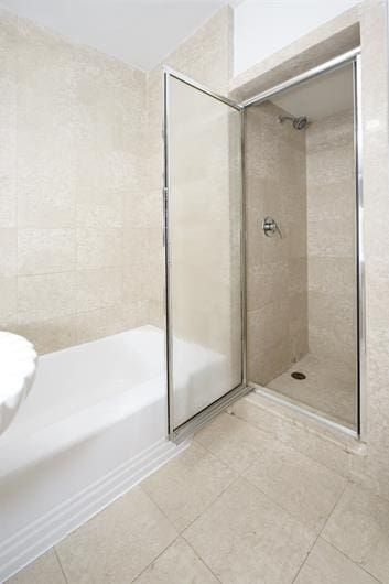 full bath featuring tile patterned floors, a shower, and a washtub