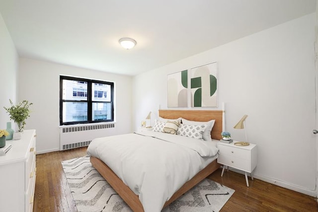 bedroom with radiator heating unit, baseboards, and wood finished floors