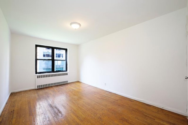 spare room with radiator, baseboards, and hardwood / wood-style flooring