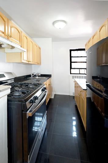 315 E 56th St Unit 6-B, New York City, NY 10022 - kitchen with stainless steel gas range, light brown cabinetry, a sink, under cabinet range hood, and baseboards