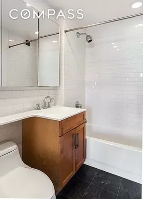 full bathroom featuring toilet, tasteful backsplash, tile walls, vanity, and tiled shower / bath combo