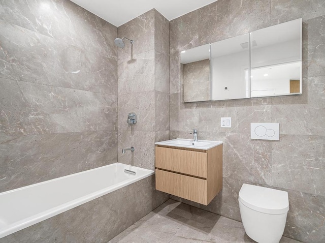 bathroom with tile walls, tiled shower / bath, toilet, and vanity