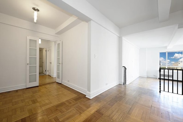 spare room featuring baseboards and beam ceiling