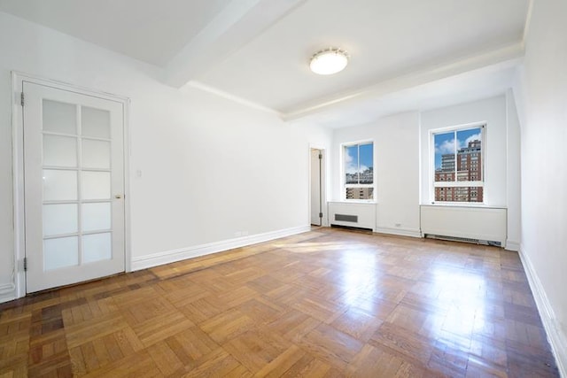 spare room featuring beam ceiling and baseboards