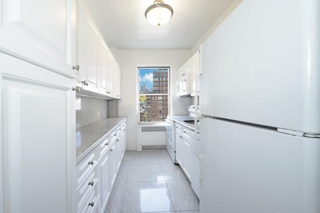 kitchen with white appliances, white cabinets, radiator, light countertops, and light speckled floor