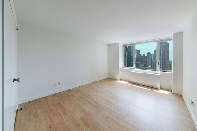 empty room with radiator heating unit and light hardwood / wood-style floors