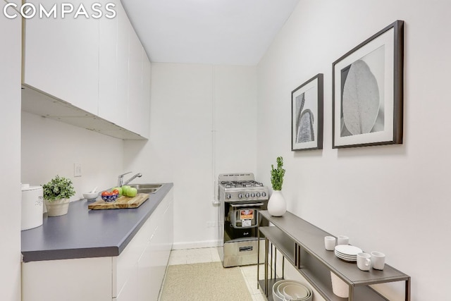 interior space featuring white cabinetry, sink, and high end range