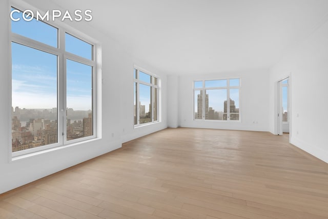 unfurnished room featuring a city view and light wood-type flooring