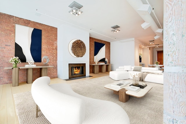 living room featuring brick wall and light hardwood / wood-style floors