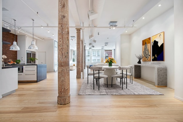 dining space with light hardwood / wood-style flooring and decorative columns