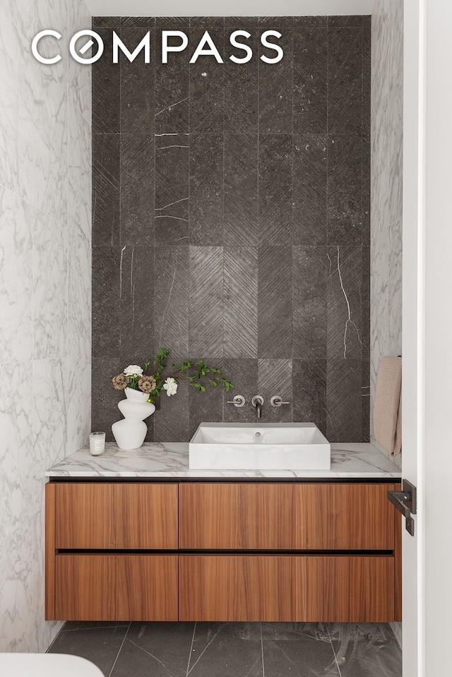bathroom with marble finish flooring and a sink