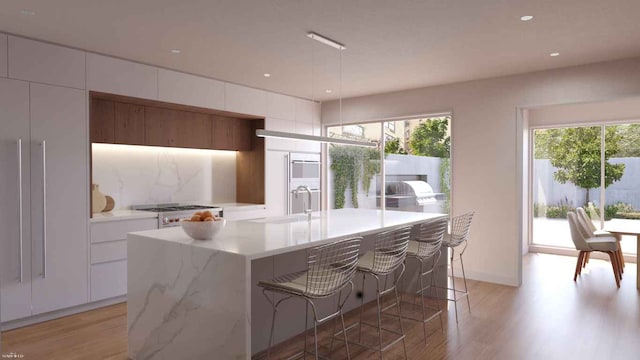 kitchen with sink, a center island with sink, plenty of natural light, white cabinets, and stove