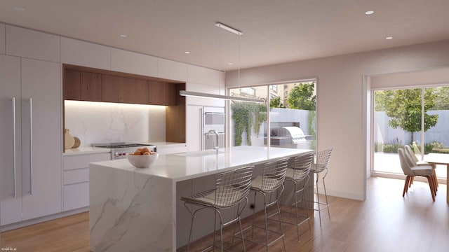 kitchen with white cabinets, range with gas cooktop, light wood-style flooring, modern cabinets, and a sink