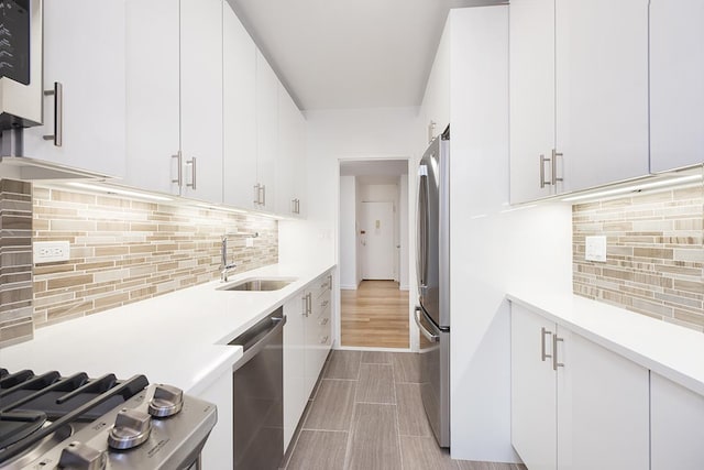 kitchen featuring white cabinets, stainless steel appliances, light countertops, and a sink