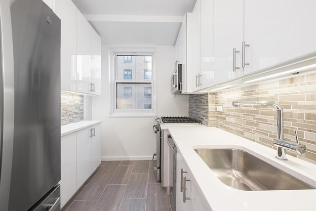 kitchen featuring white cabinets, decorative backsplash, sink, and stainless steel appliances