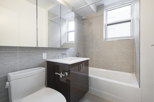 full bathroom with tiled shower / bath combo, tile patterned floors, vanity, tile walls, and toilet