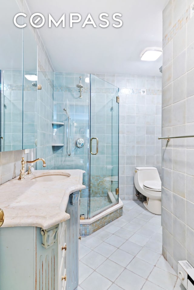 full bathroom featuring tile patterned floors, toilet, a stall shower, tile walls, and vanity