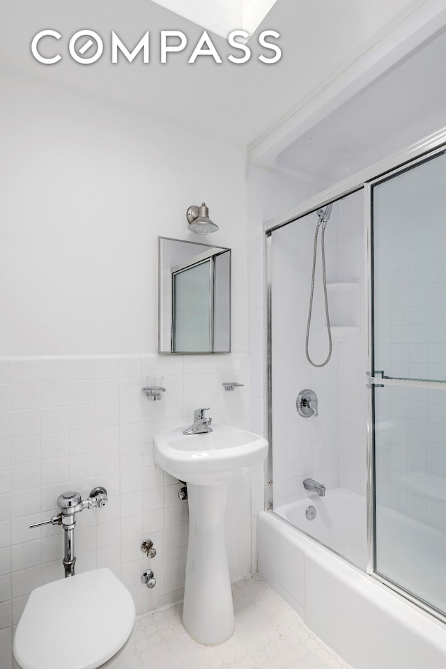 bathroom with shower / bath combination with glass door, tile walls, and toilet