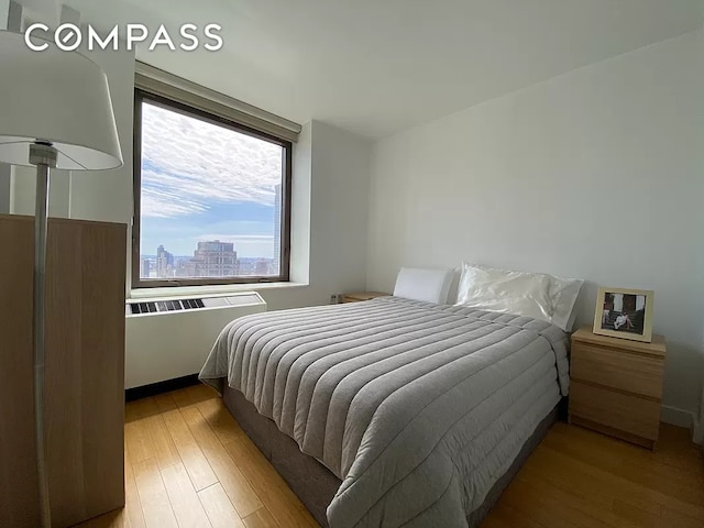 bedroom featuring radiator, a view of city, and wood finished floors