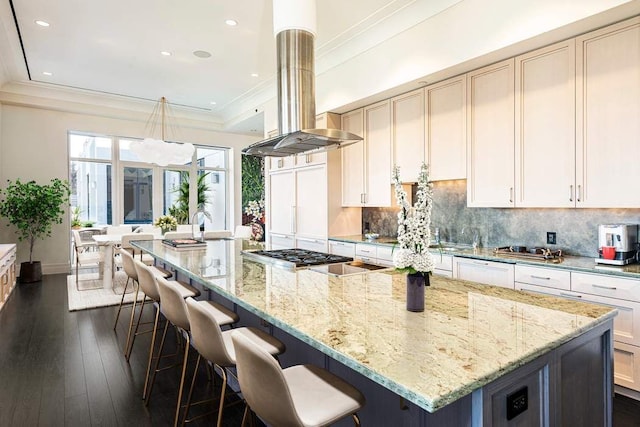 kitchen featuring decorative backsplash, island exhaust hood, a large island, light stone countertops, and dark wood-type flooring