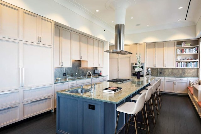 kitchen featuring sink, extractor fan, appliances with stainless steel finishes, an island with sink, and light stone countertops