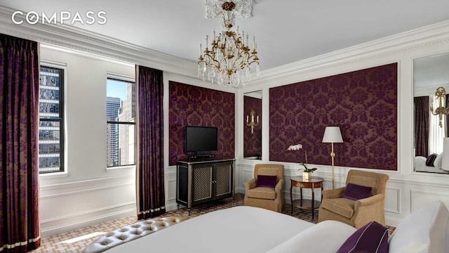 bedroom featuring a chandelier, wallpapered walls, ornamental molding, and a decorative wall