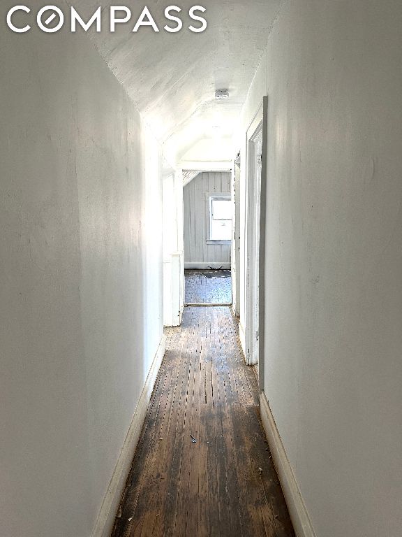 hallway with vaulted ceiling and dark hardwood / wood-style flooring