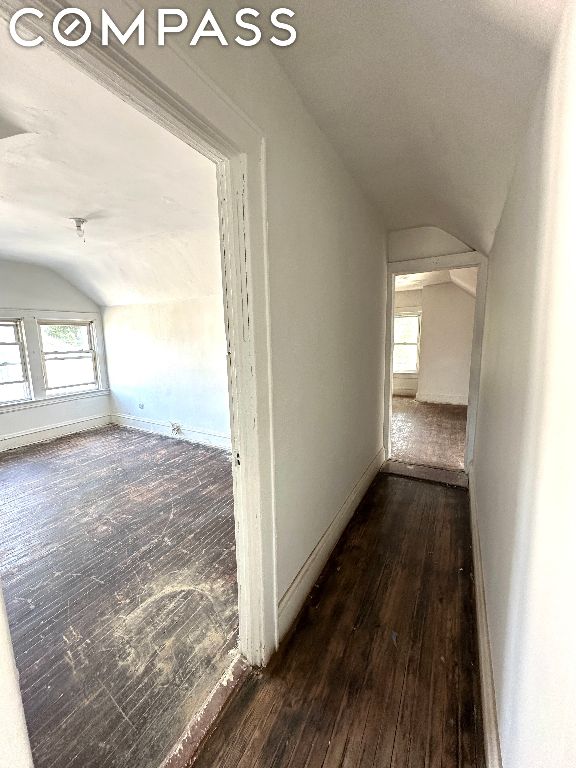 corridor with vaulted ceiling and dark hardwood / wood-style flooring