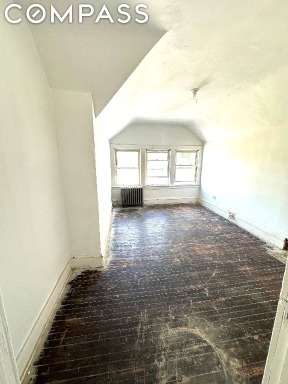 additional living space featuring radiator and vaulted ceiling