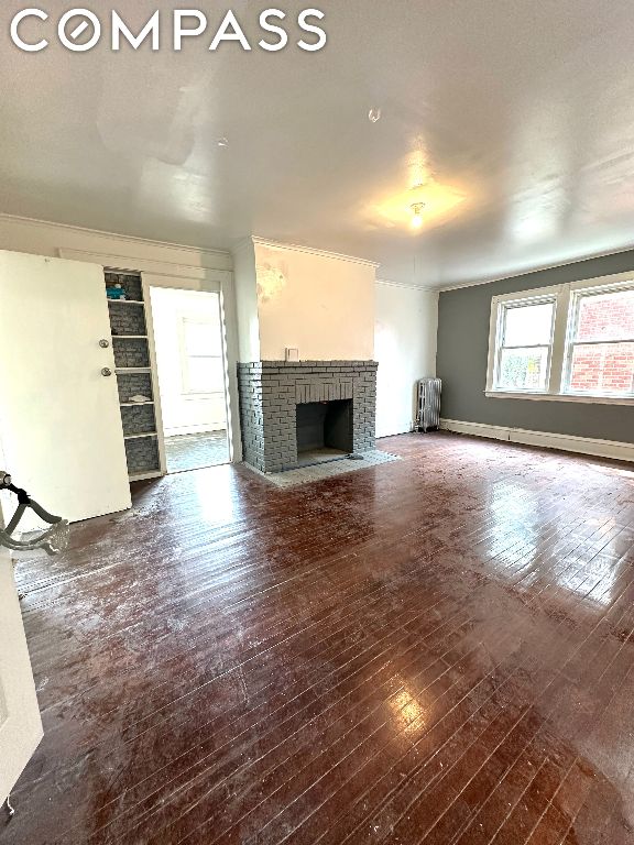 unfurnished living room featuring dark hardwood / wood-style floors, radiator, and a fireplace