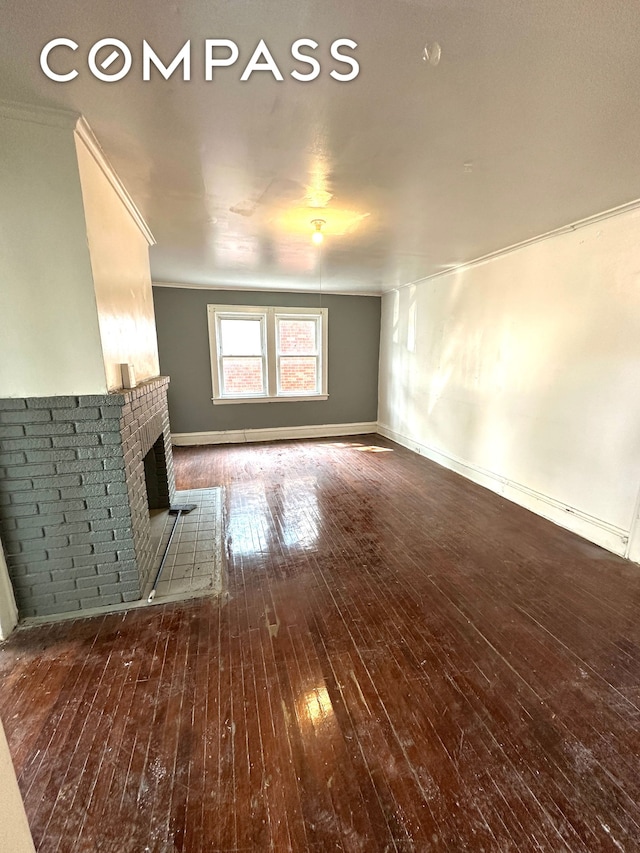 unfurnished living room featuring ornamental molding, a brick fireplace, wood-type flooring, and baseboards