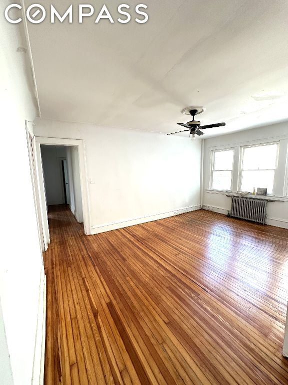 spare room with ceiling fan, radiator heating unit, and hardwood / wood-style floors